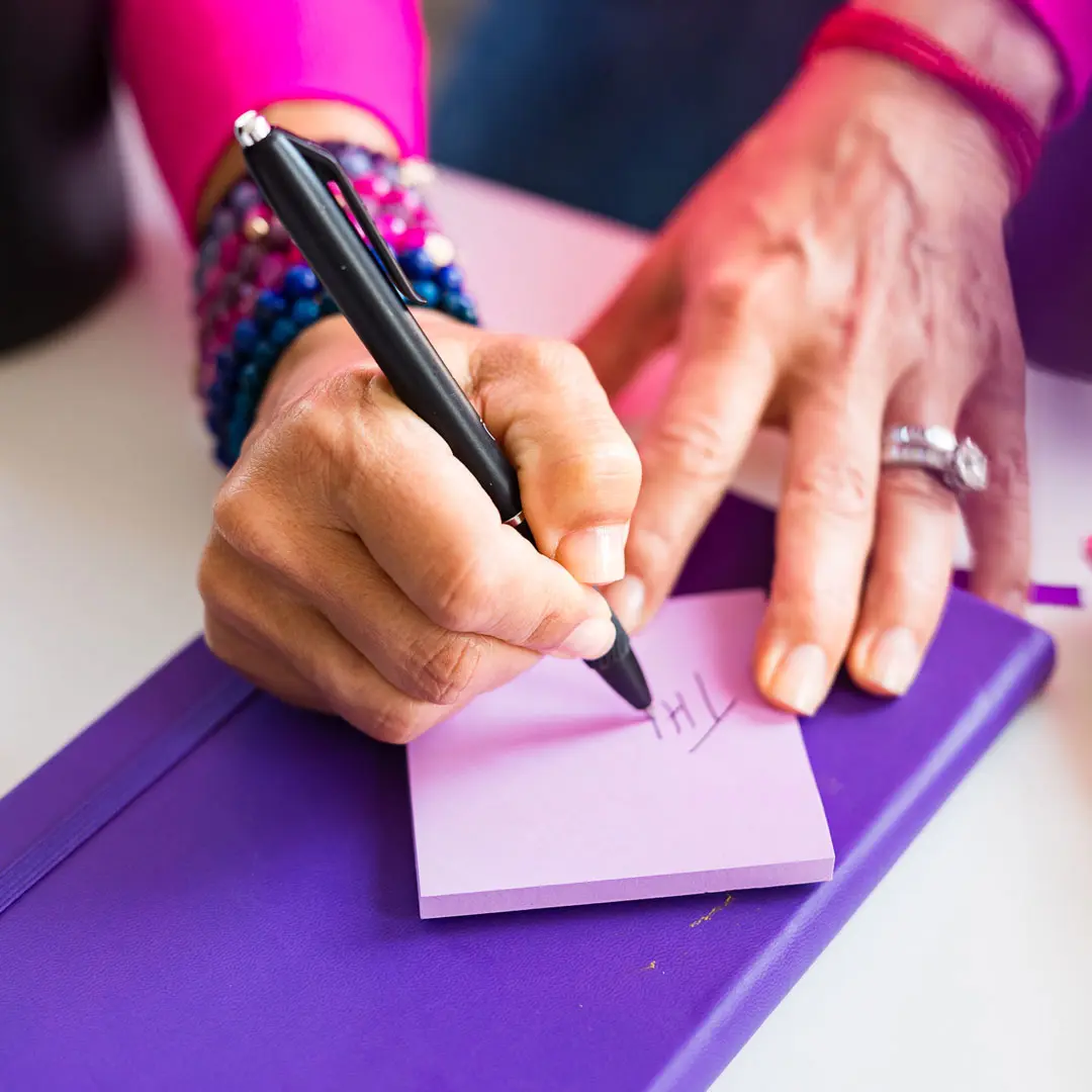 Julie Kaminski, board-certified health coach, writing personalized wellness goals during a one-on-one coaching session using the SAVOR Method.